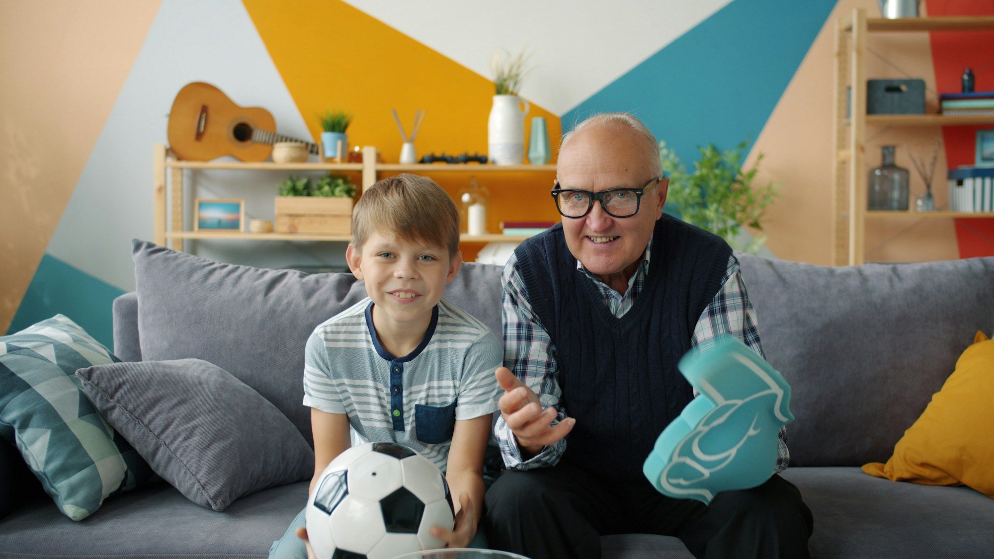 Opa en kleinzoon juichen voor een voetbalwedstrijd op tv