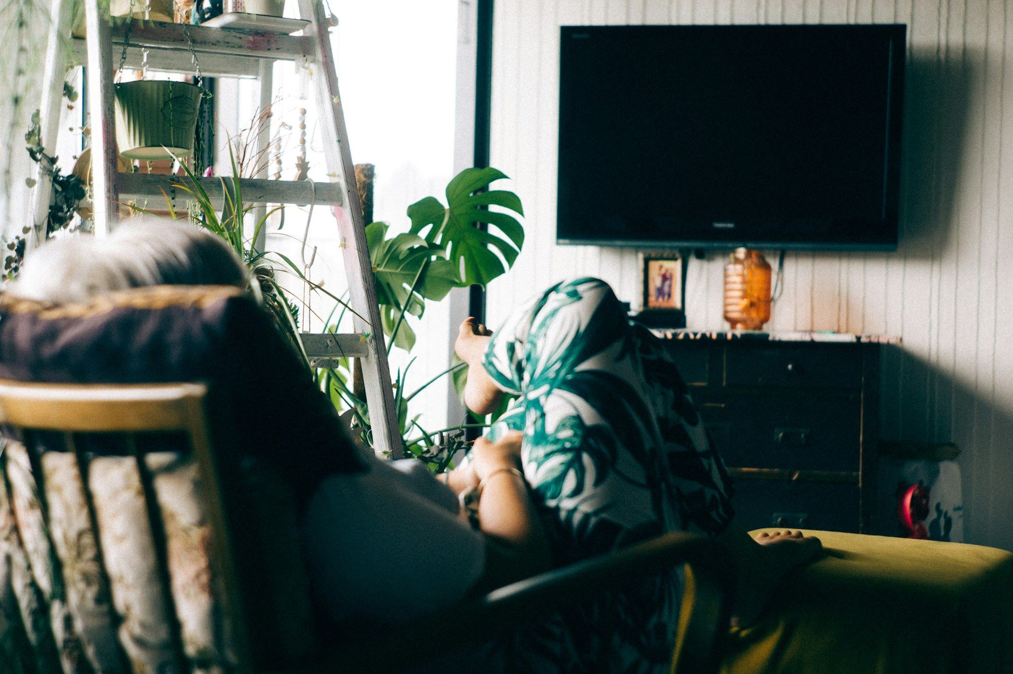 Vrouw in een fauteuil kijkt naar een tv die uit staat